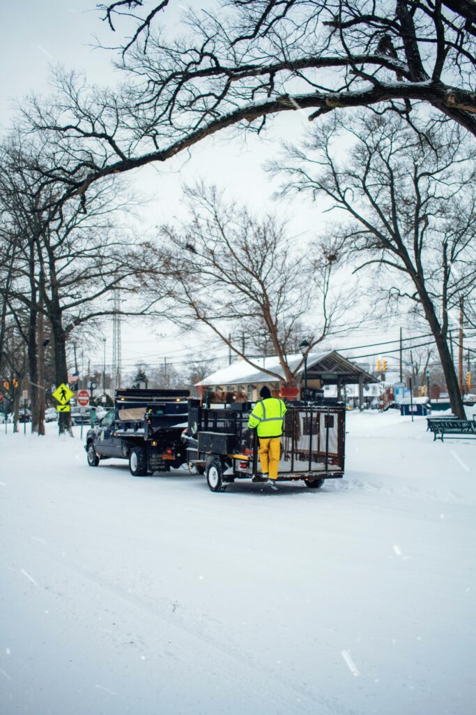 Urban winter scene featuring snow removal workers and equipment in a snowy city street.