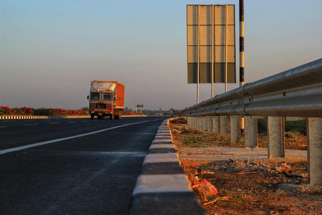 A solitary truck travels down a deserted highway at sunset, with clear blue skies overhead.